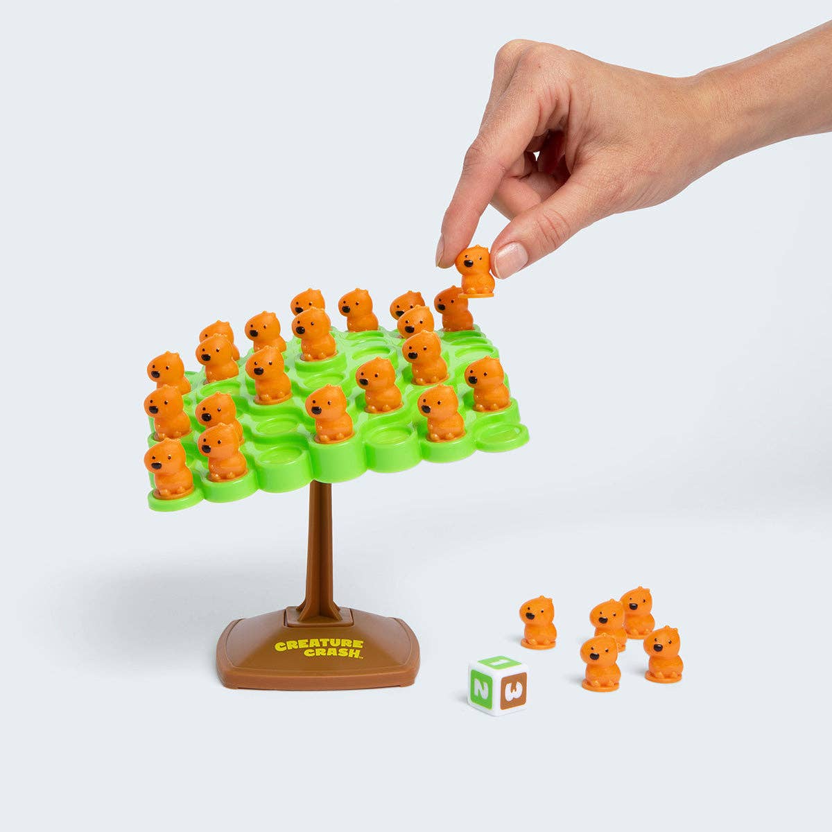 Hand playing with a 'Creature Crash' game on a white background
