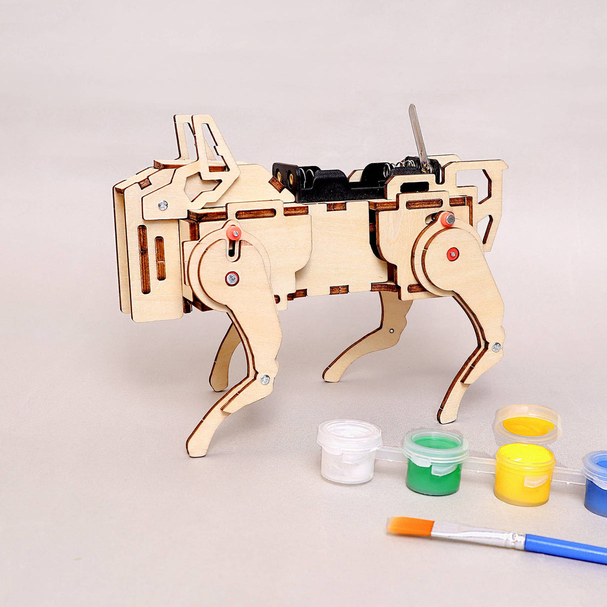 Wooden robot dog model with paint cans and a brush on a light gray background
