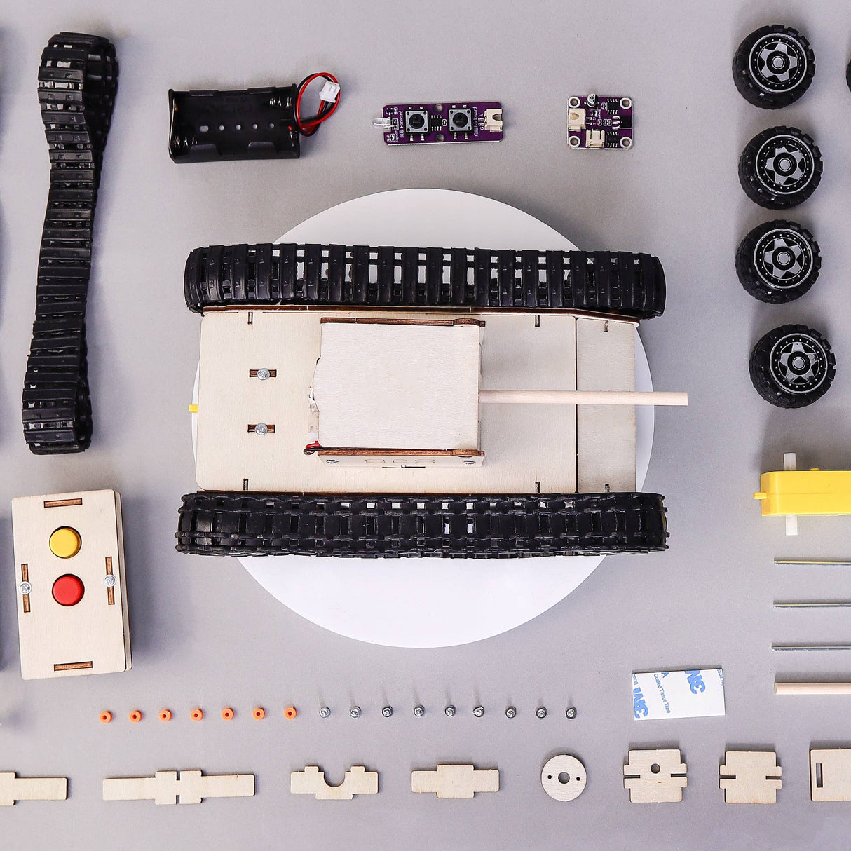 Robotics components including a tank-like chassis, wheels, and electronic parts on a gray background