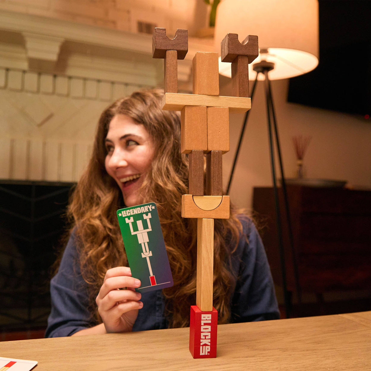 Woman playing with a wooden block tower game at a table.