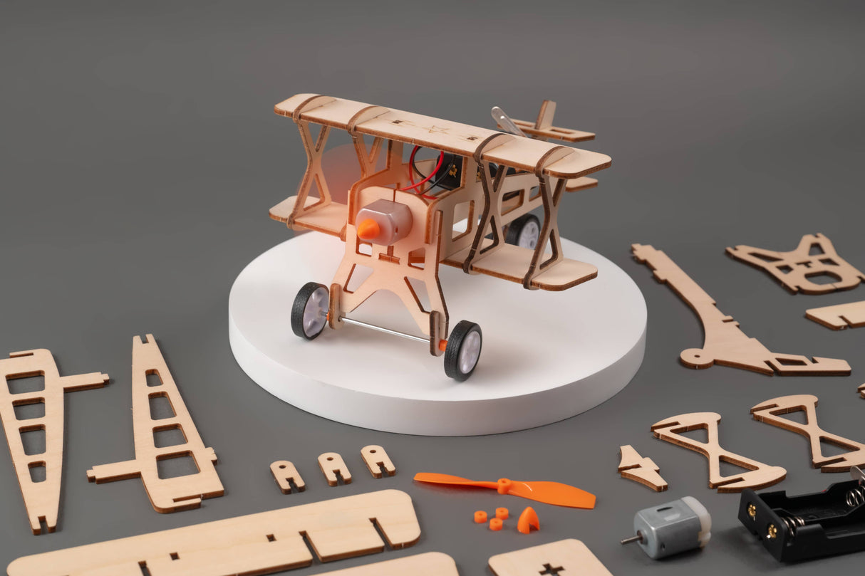 Wooden airplane model kit with components on a gray background