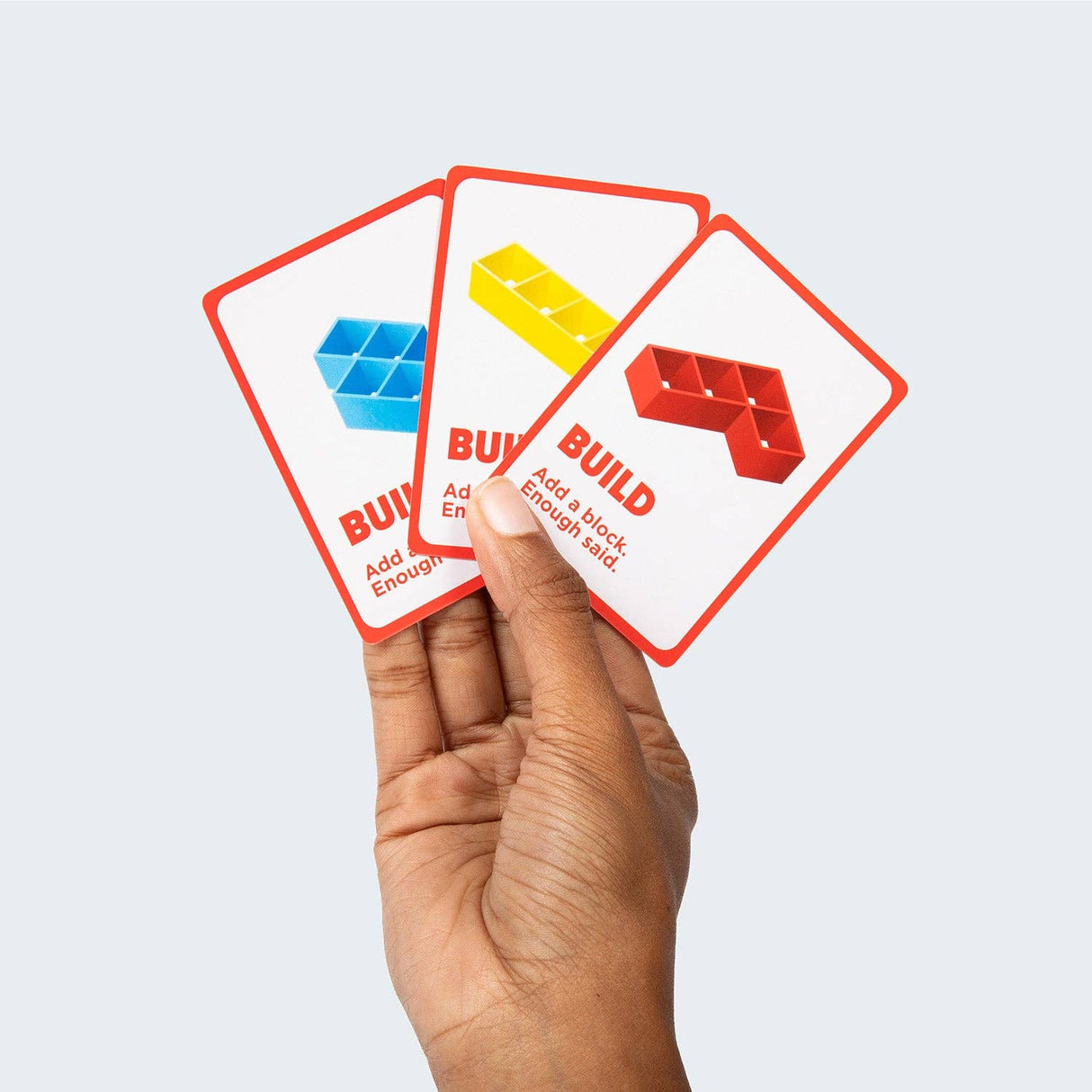 Hand holding three card tiles with colorful block illustrations and text on a light gray background