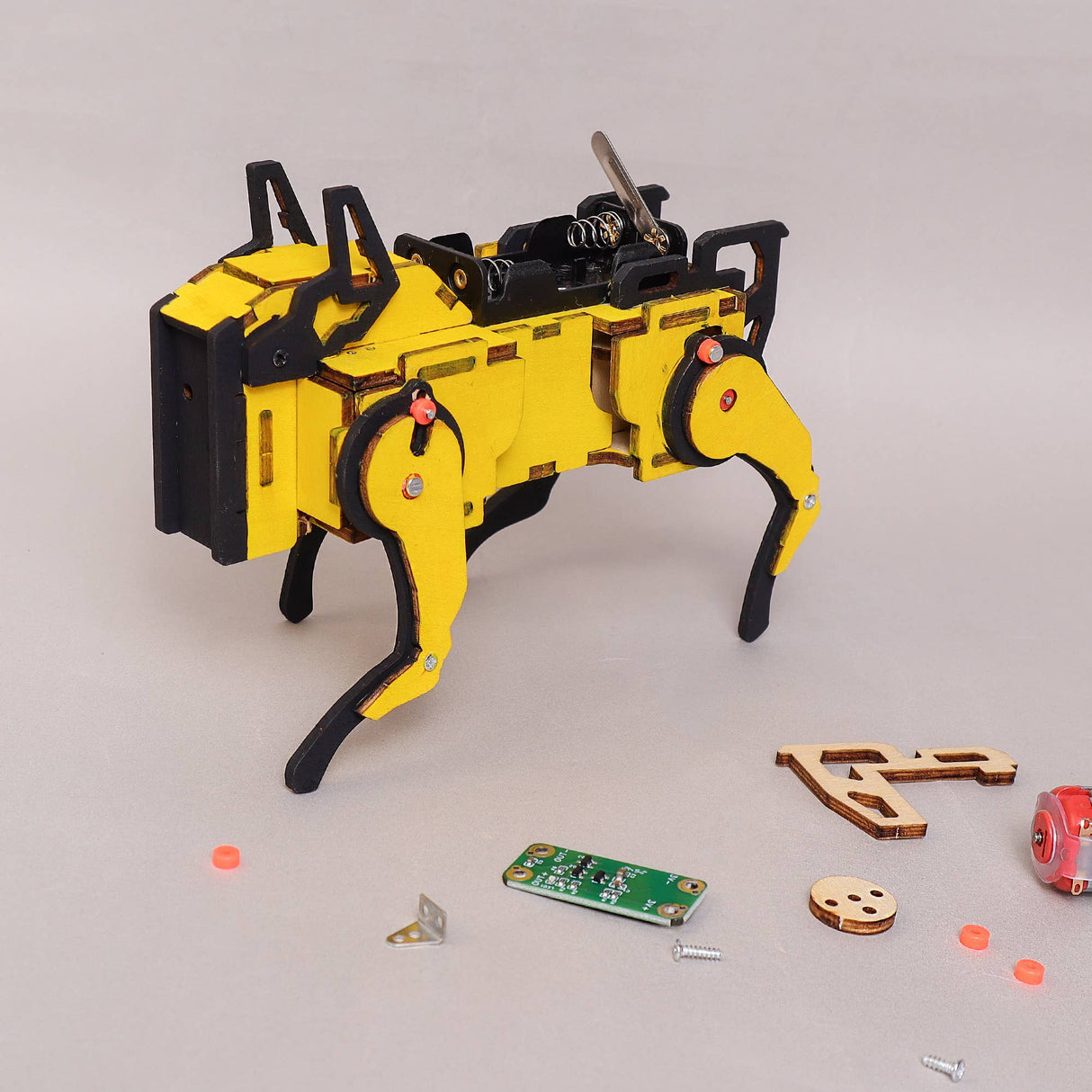 Yellow and black robot model with scattered parts on a light gray background