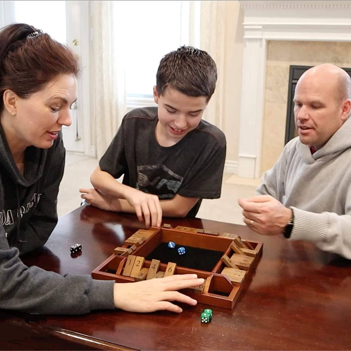 Three people playing a board game together in a room with large windows.