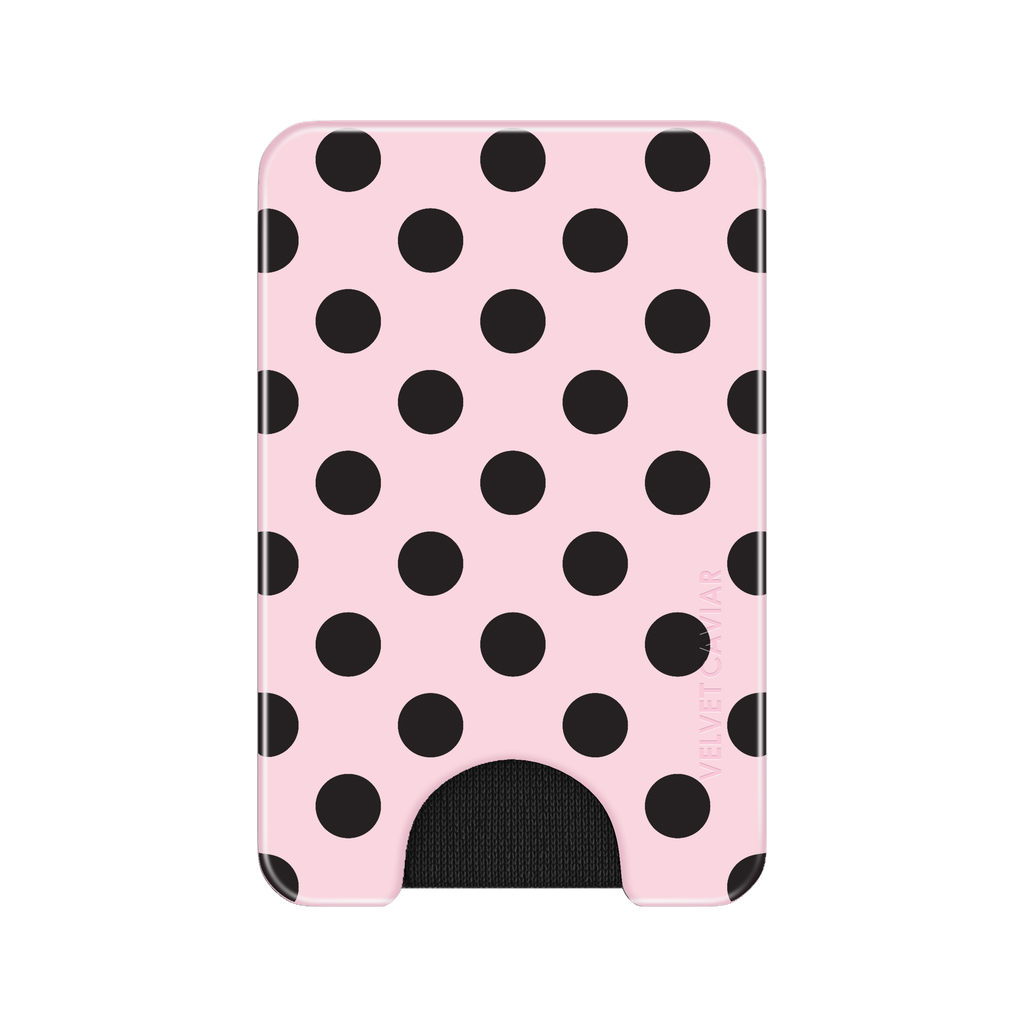 A slim pink wallet or card holder with a black polka dot pattern and a black cutout at the bottom, shown on a plain white background.