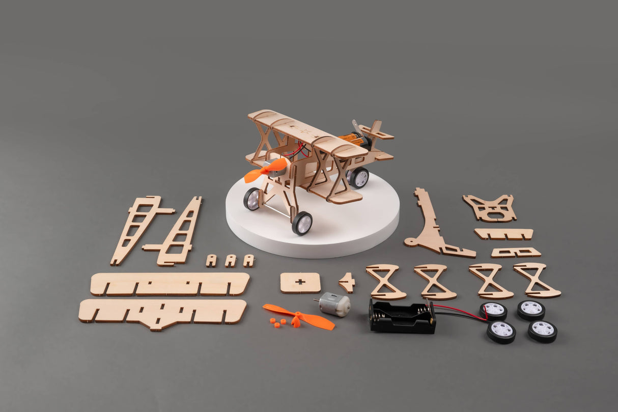 Wooden model airplane kit with components on a gray background