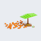 Board game components including orange tokens, a green tree-like structure, and a brown base on a white background.