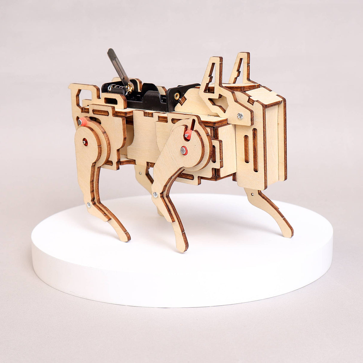 Wooden mechanical model of a robot on a white platform