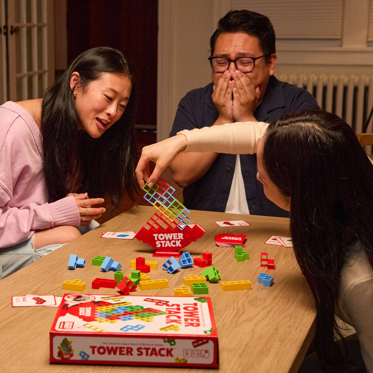 People playing a board game called 'Tower Stack' at a table.