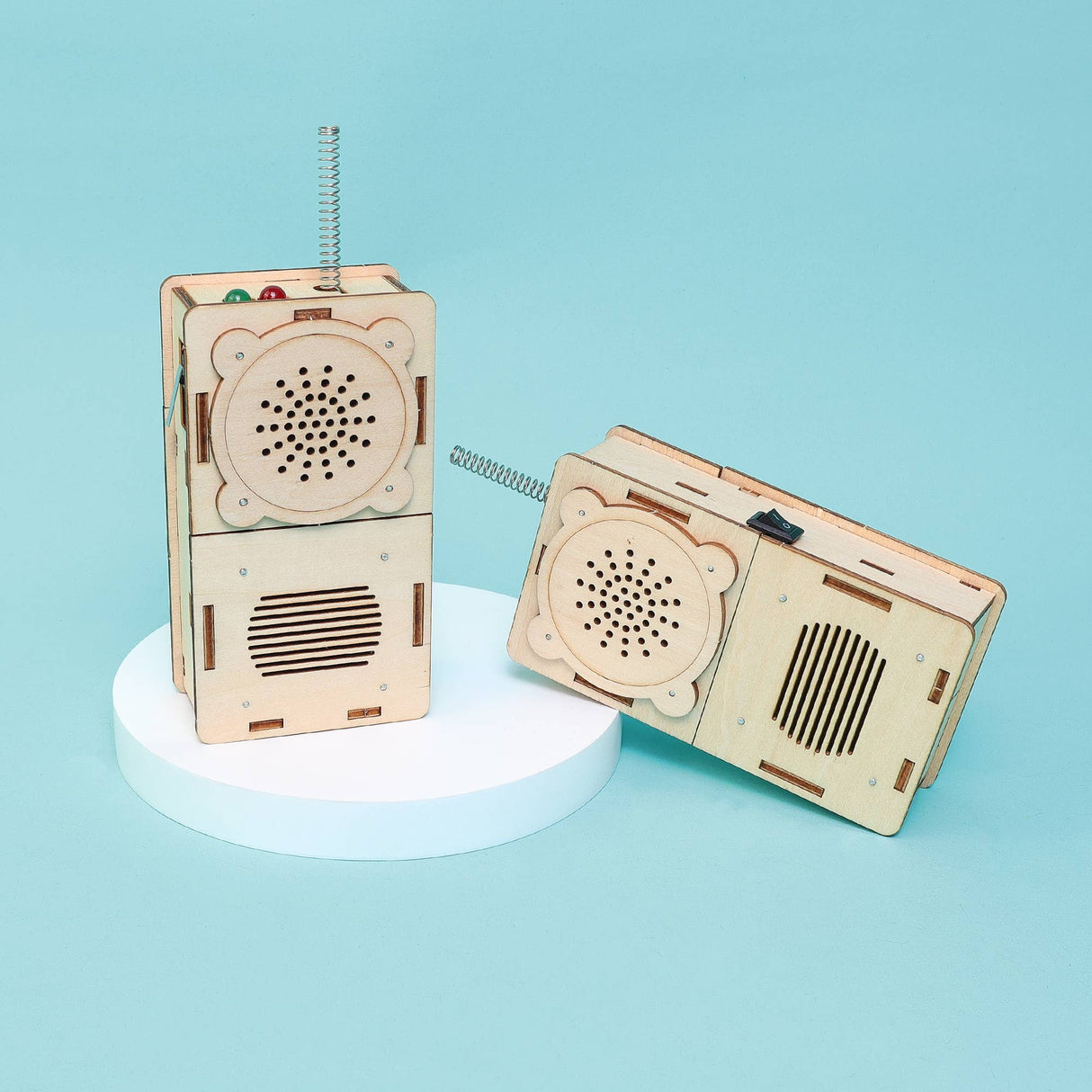 Two wooden mechanical devices resembling vintage radios on a light blue background