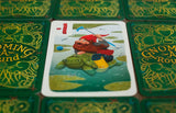 Card game with a gnome on a turtle illustration surrounded by green game boards.