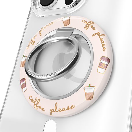 A clear phone case with a circular light pink protective bumper featuring 'coffee please' script and iced coffee illustrations. The bumper includes a silver metallic ring stand in the center.