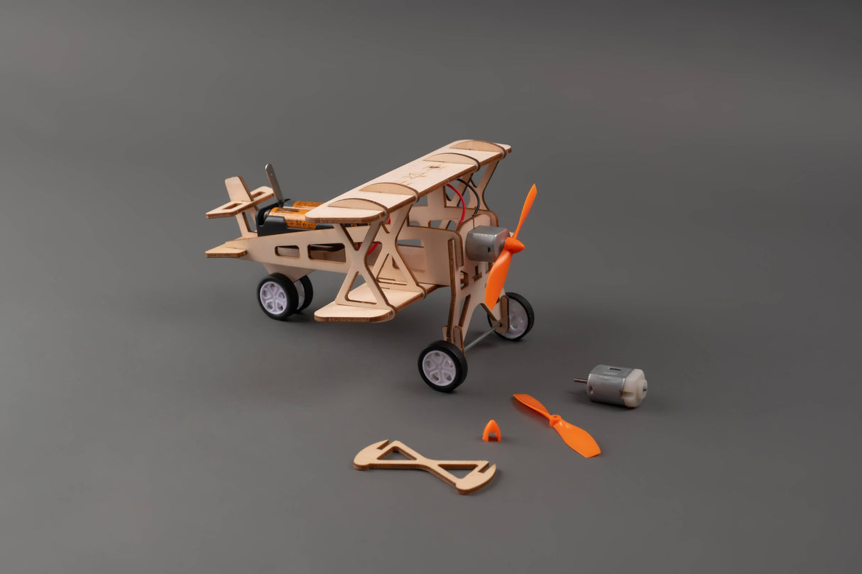 Wooden model airplane kit with unassembled parts on a gray background