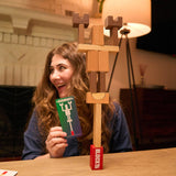 Woman playing with a wooden block tower game at a table.