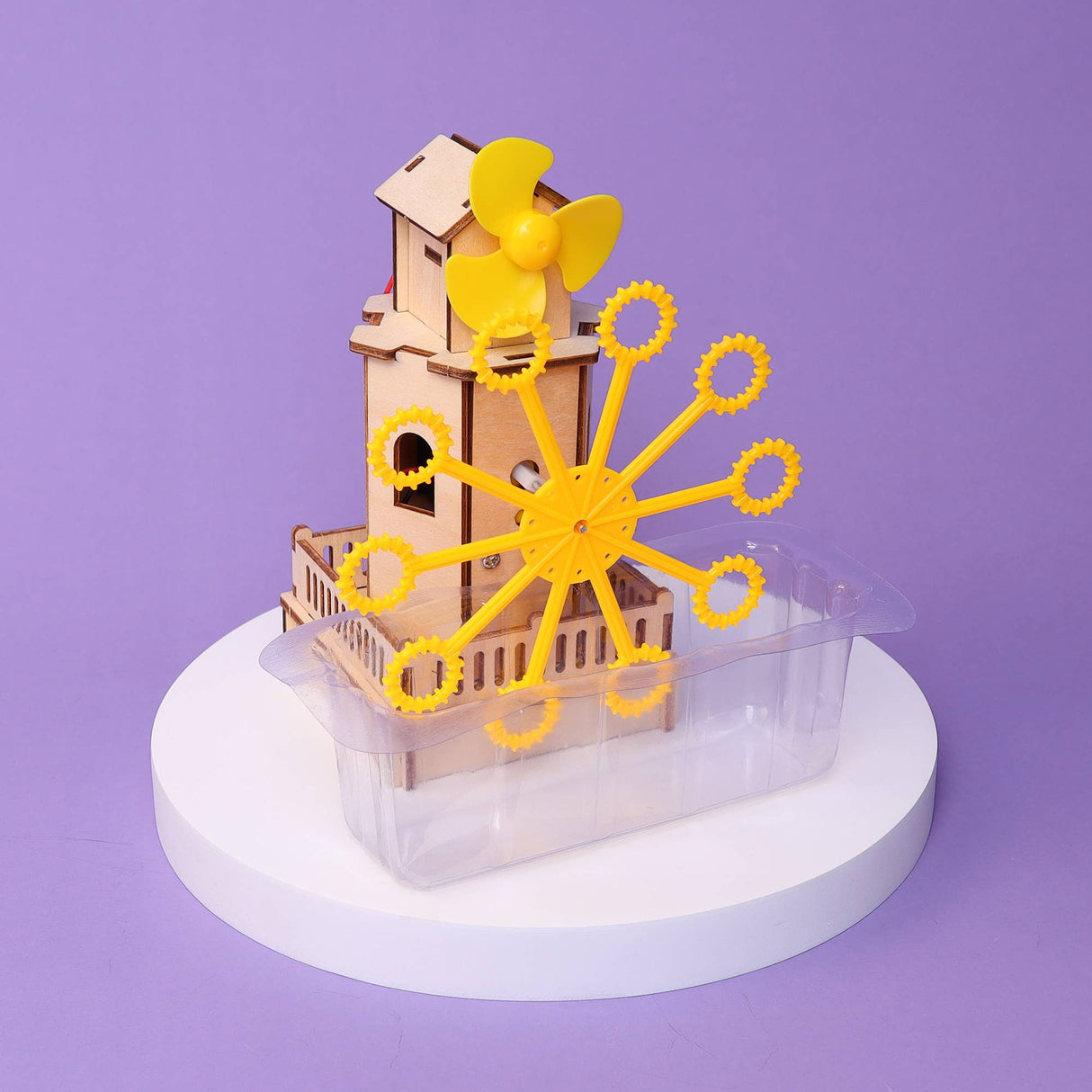 Wooden model of a clock tower with yellow gears on a purple background