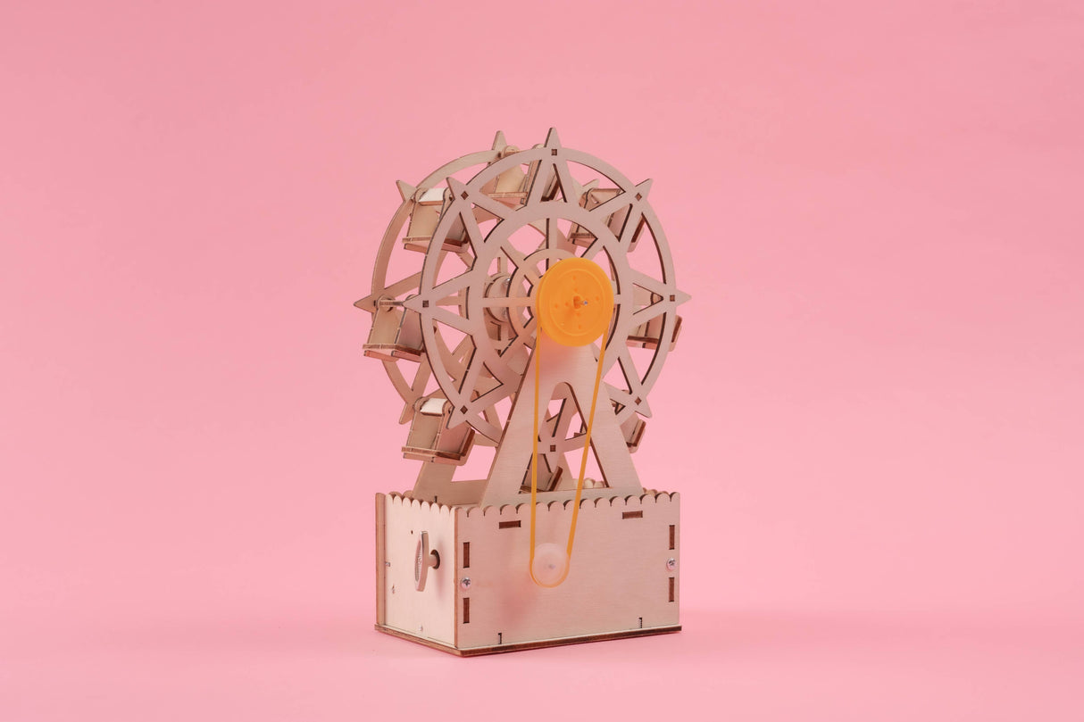 Wooden model of a Ferris wheel on a pink background