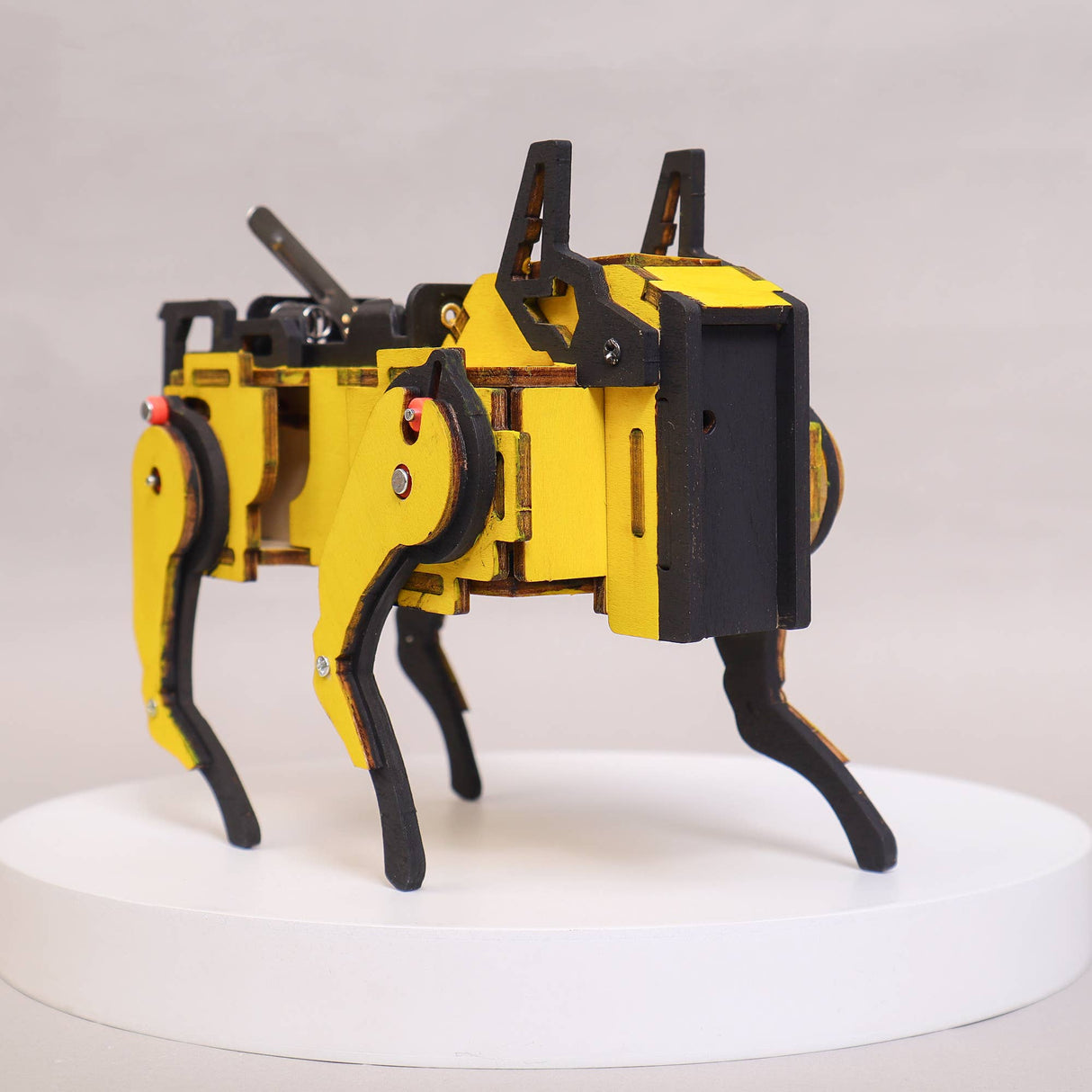 Yellow and black robot on a white platform with a light gray background