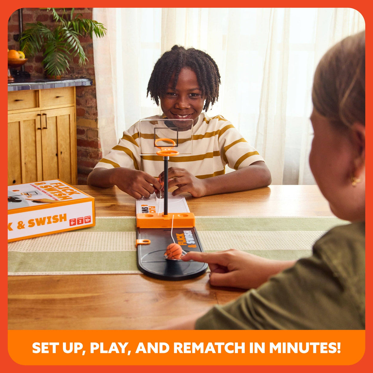 Two children playing with a 'Push & Swish' game at a table.