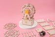Wooden model kit of a Ferris wheel on a pink background