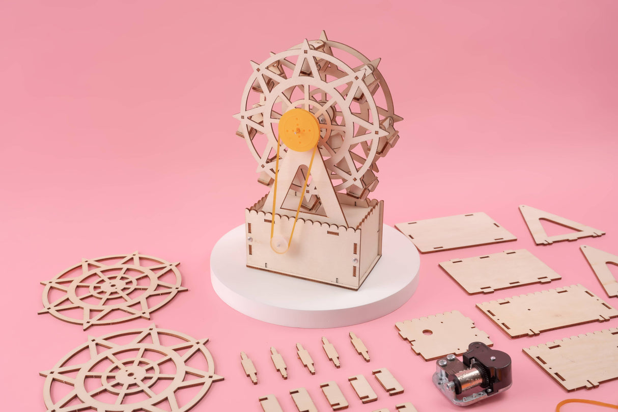 Wooden model kit of a Ferris wheel on a pink background