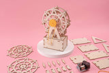 Wooden model kit of a Ferris wheel on a pink background