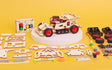 Mechanical model kit with assembled vehicle and unassembled parts on a yellow background