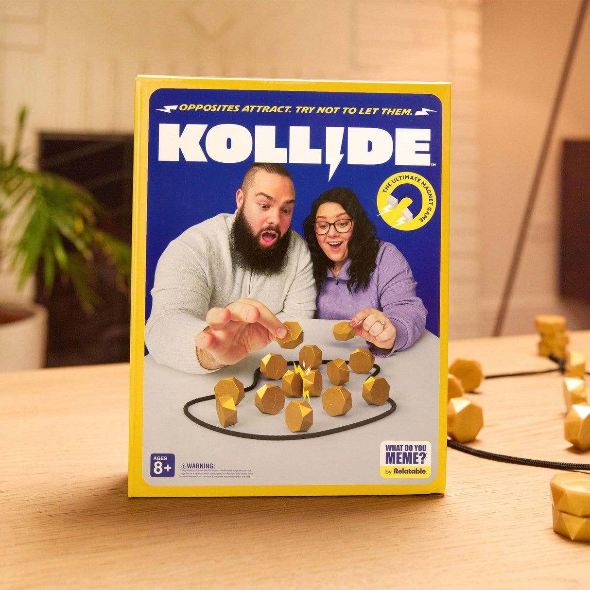 Kollide board game box with two people and game pieces on a wooden surface
