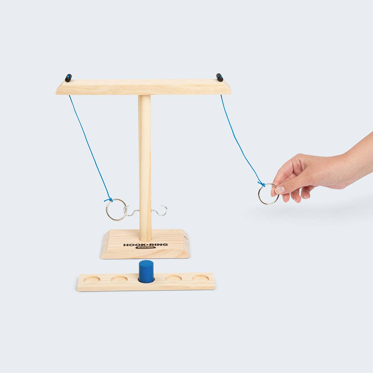 Wooden ring game with a hand interacting with it on a white background